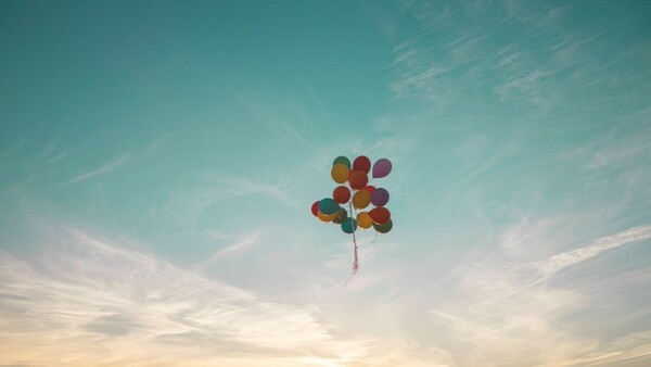 Luftballons fliegen am Himmel.