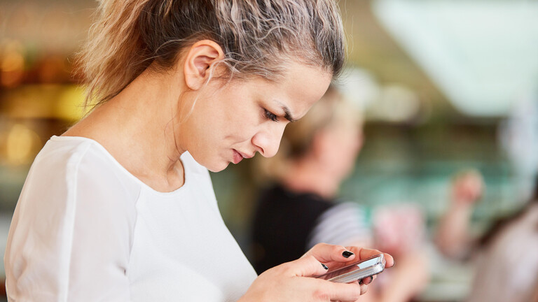 Frau schaut nachdenklich aufs Smartphone