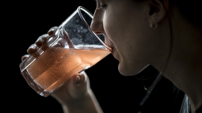 Eine Frau trinkt ein Glas Wasser mit aufgelöster Eisentablette