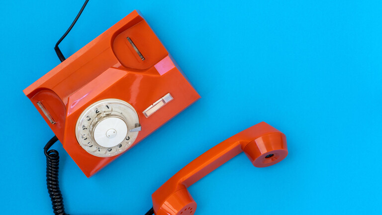 Rotes Wählscheibentelefon auf blauem Hintergrund