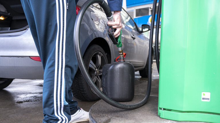 Ein Mann tankt an einer Tankstelle Benzin in einen Kanister.