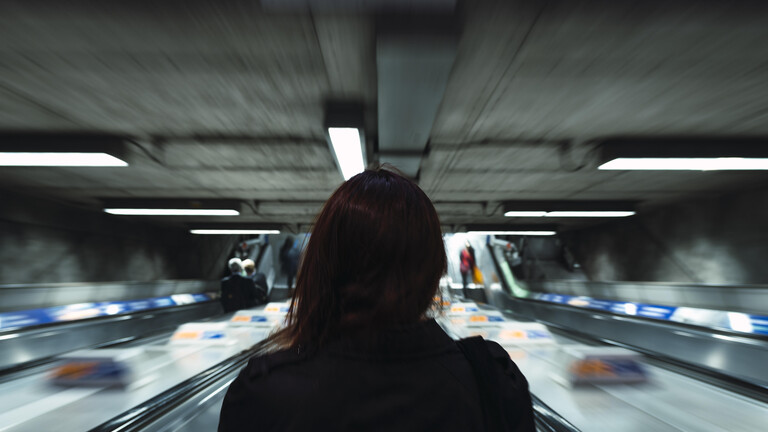 Frau fährt Rolltreppe hinunter