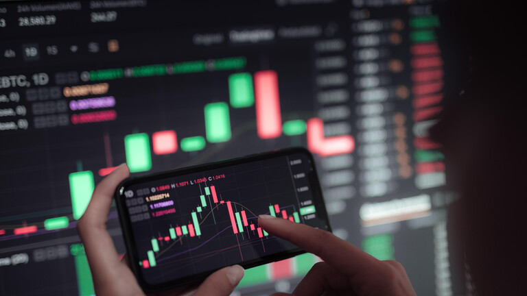 Verlauf eines Aktienkurses auf großem Bildschirm und auf einem Smartphone