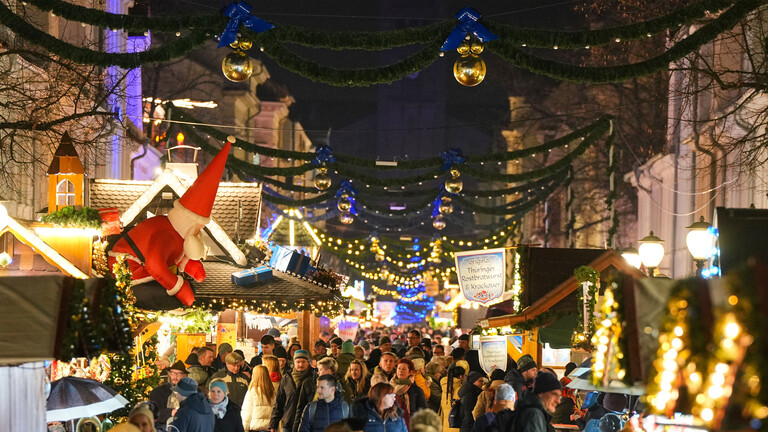 Passanten gehen in der Brandenburger Straße zwischen den Buden des Weihnachtsmarktes in der Innenstadt entlang