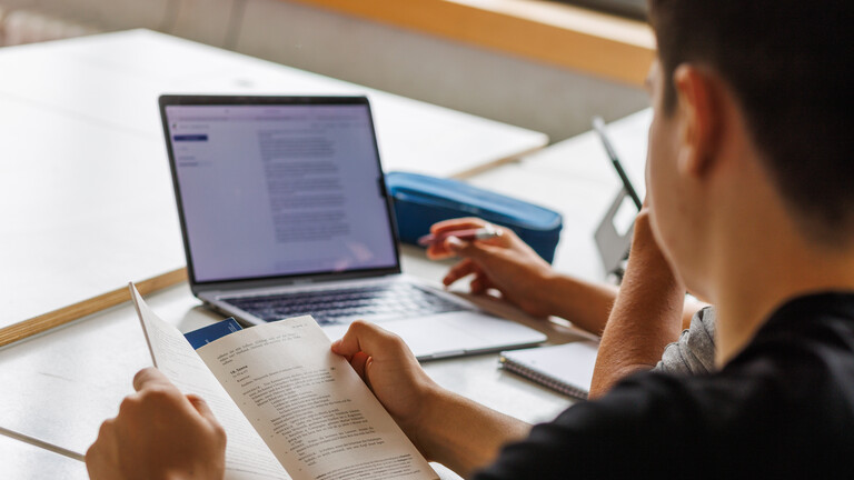Schüler sitzen vor einem Laptop und benutzen ein KI-Tool.