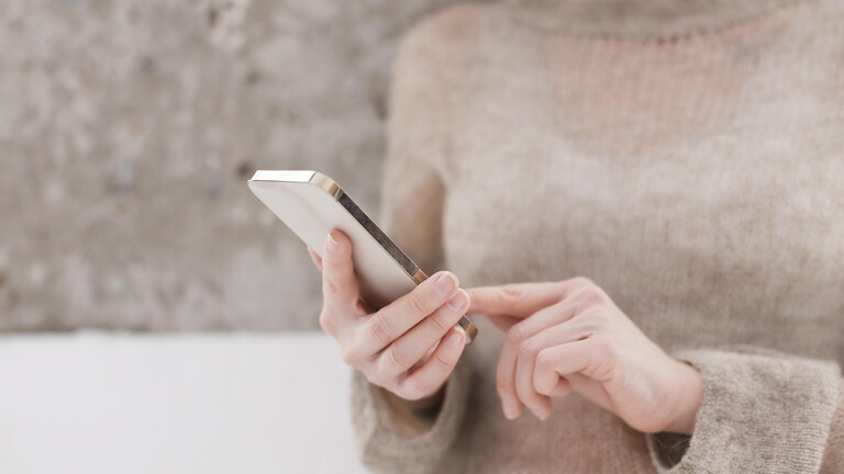Frau hebt Zeigefinger, um auf Smartphone zu tippen