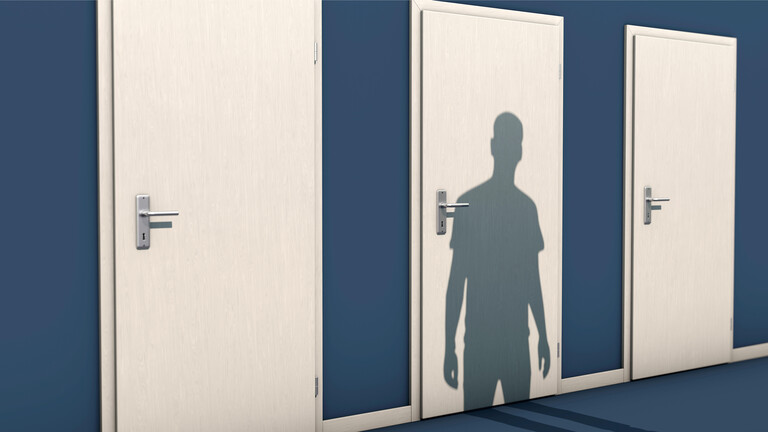 Drei weiße Türen nebeneinander, auf die mittlere Tür liegt der Schatten eines Mannes