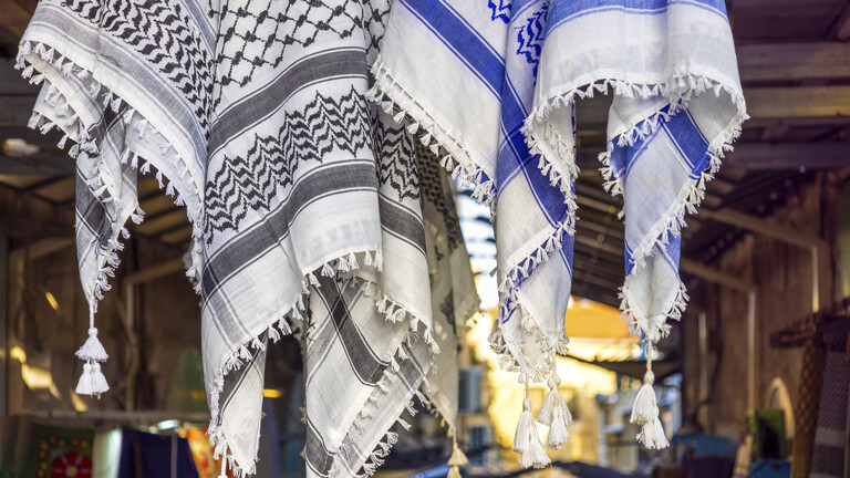 Eine schwarz-weiße und eine blau-weiße Kufiya hängen nebeneinander in der Jerusalemer Altstadt