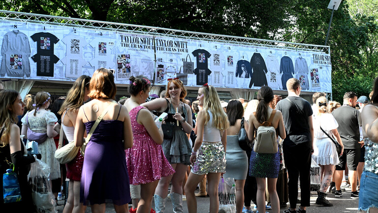 Fans von Taylor Swift stehen in einer Schlange vor dem Einlass zum Konzert und vor dem Merchandise-Stand.