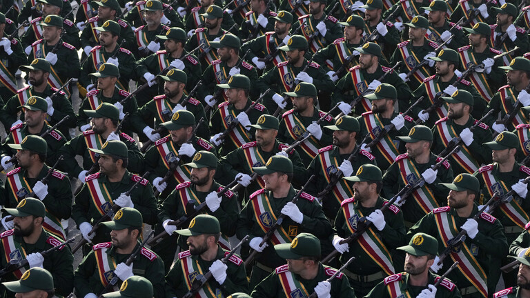 Soldaten der iranischen Revolutionsgarden marschieren durch Teheran bei einer Parade. Die Soldaten blicken alle nach rechts, sie tragen eine Waffe.