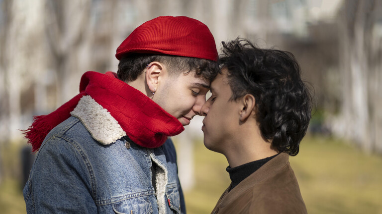 Zwei junge Männer küssen sich in einem Park