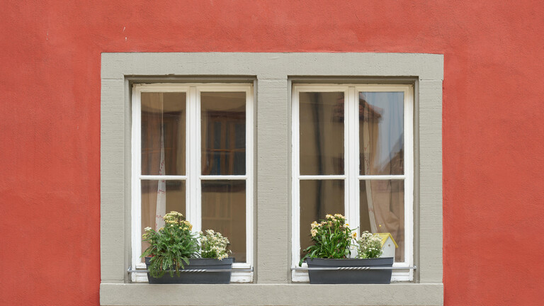 Fenster eines roten Hauses mit Blumen auf dem Fensterbrett