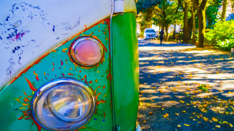 Ein grüner Vintage-Van auf einer herbstlichen Straße
