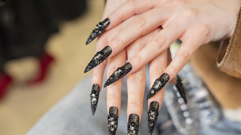 Nahaufnahme von langen schwarz lackierten Fingernägeln