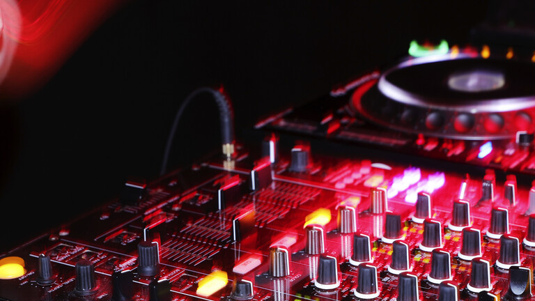 Ein DJ-Pult in schummrig-rotem Licht.