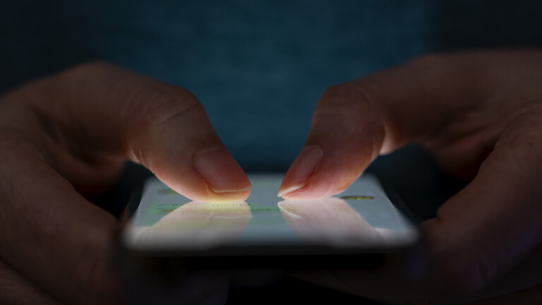 Ein Mensch hält ein Handy mit beiden Daumen auf dem Dsiplay