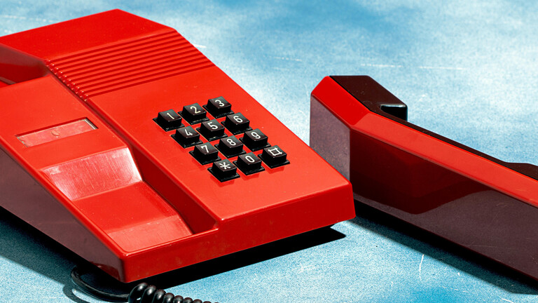 Altes rotes Telefon auf einem Wolkenhimmel-Hintergrund