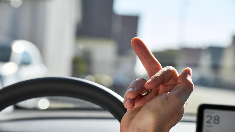 Autofahrer zeigt den Mittelfinger.