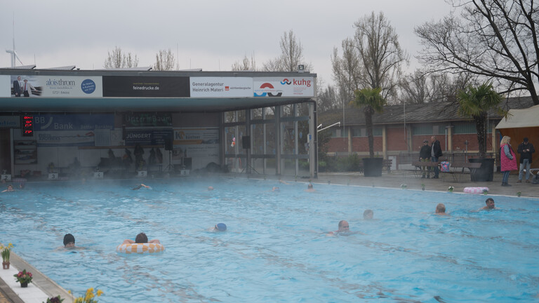 Zahlreiche Badegäste schwimmen im Freibad. Das Sonnenbad Karlsruhe startet als eines der ersten Freibäder Deutschlands in die neue Badesaison