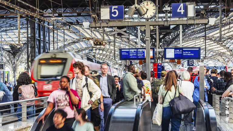 Ein Hauptbahnhof mit vielen Reisenden und Zügen