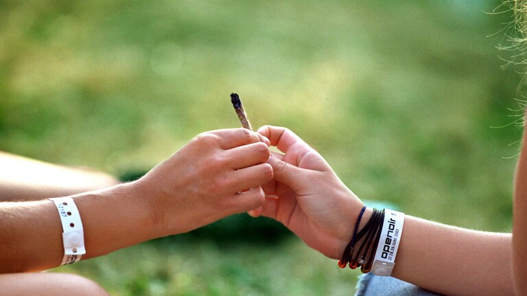 Eine Hand reicht einer anderen einen Joint