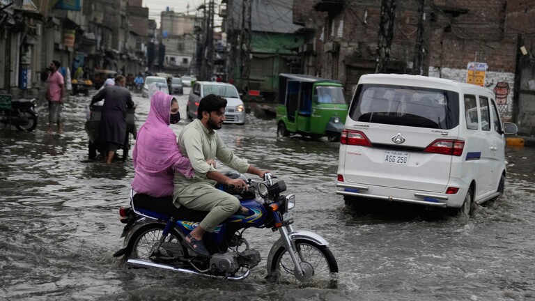 Menschen sind auf überfluteten Straßen in Lahore in Pakistan unterwegs