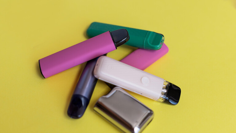 Bunte Einweg-Vape-Geräte auf gelbem Hintergrund