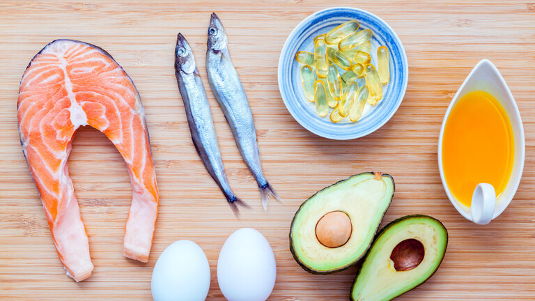 Lachs, Shishamo-Fisch, Fischöl, Avocado und Eier liegen auf einem Bambus-Schneidebrett