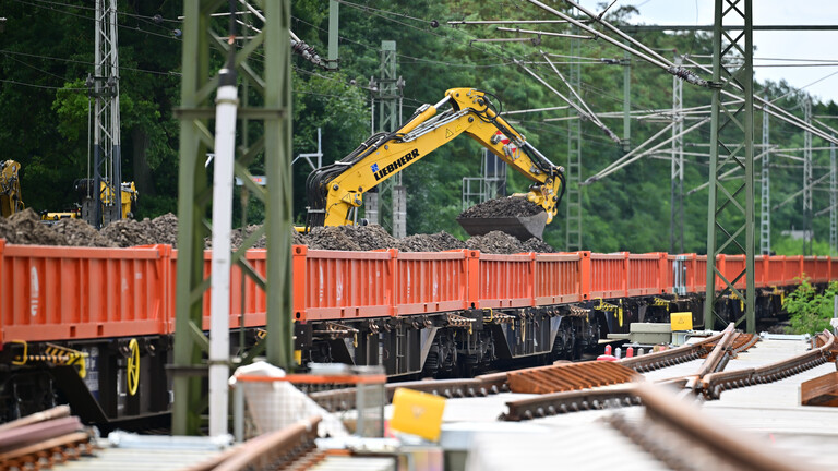 Ein Bagger hebt Schotter von einem Waggon. Das Bild zeigt die Generalsanierung der Strecke Hamburg / Berlin.