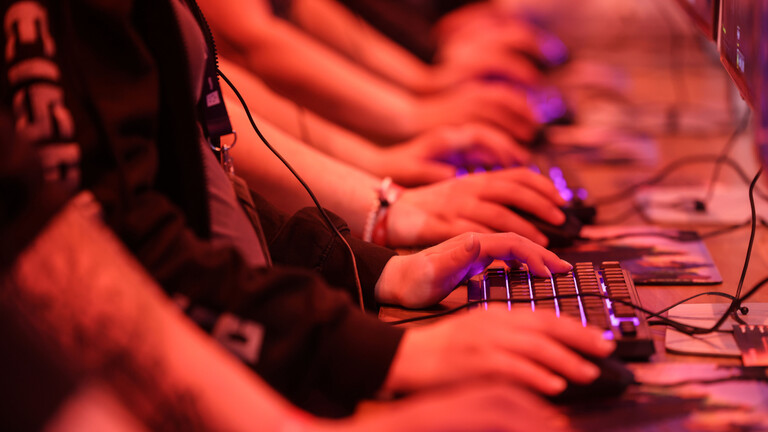 Computerspieler testen ein Spiel. Zusehen Hände und beleuchtete Gamer-Tastatur