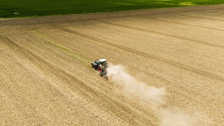 Trockenheit: Ein Landwirt fährt mit einem Traktor und einer Egge über ein Feld in der Region Hannover