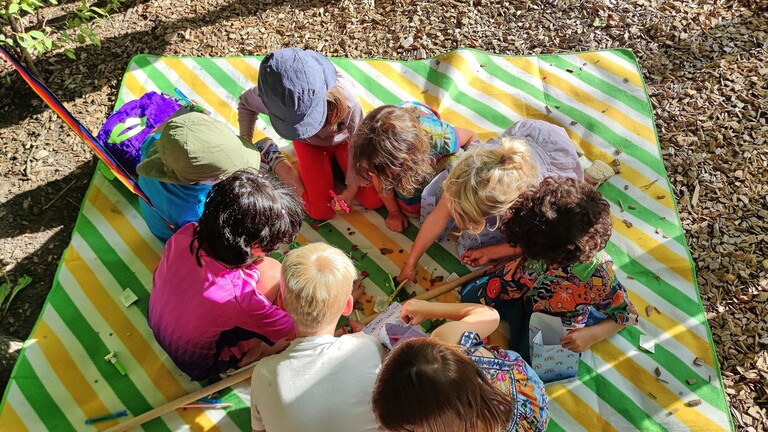Berlin, Deutschland: Kinder sitzen bei einer Geburtstagsfeier auf einer Decke und beschäftigen sich mit Süßigkeiten