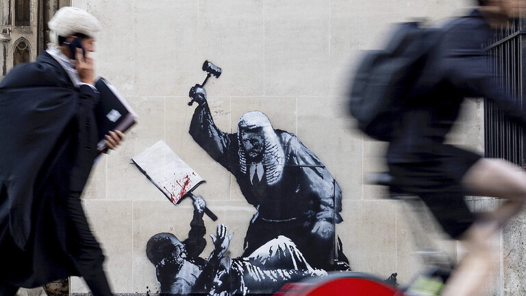 Ein von Banksy veröffentlichtes, undatiertes Foto des neuen Kunstwerks des Künstlers, das einen Richter zeigt, der im Royal Courts of Justice in London einen Demonstranten mit einem Hammer schlägt.