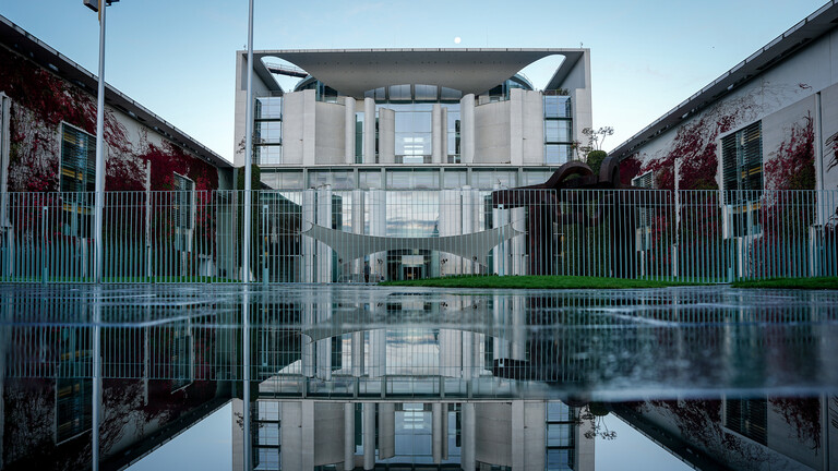 Das Bundeskanzleramt spiegelt sich in einer Pfütze