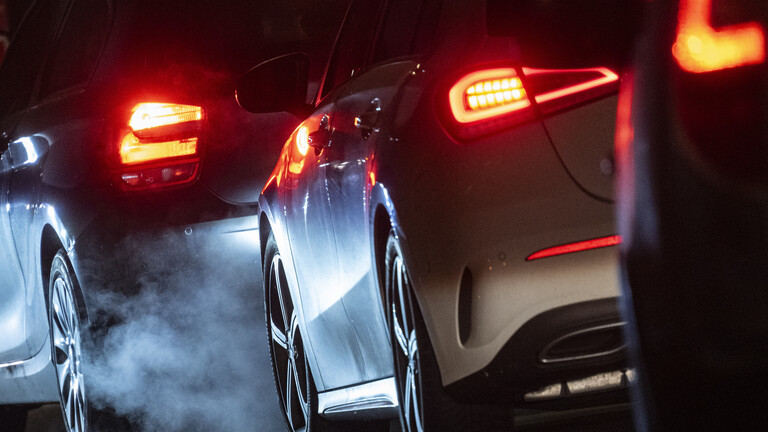 Autoabgase sind hinter einem Kraftfahrzeug im Straßenverkehr zu sehen.