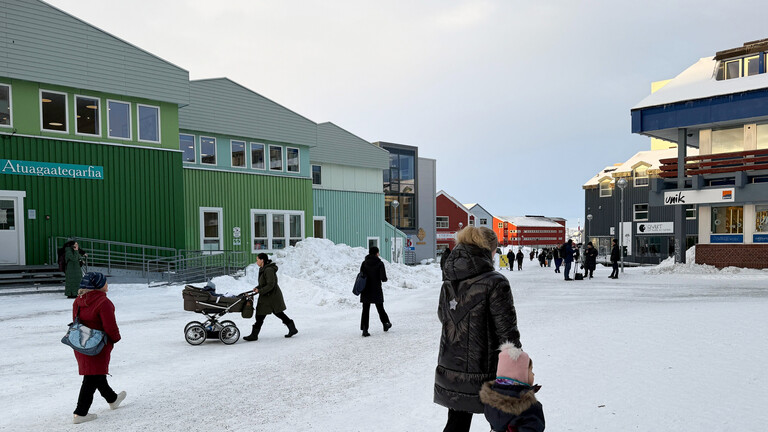 Menschen gehen durch die Innenstadt von Nuuk.