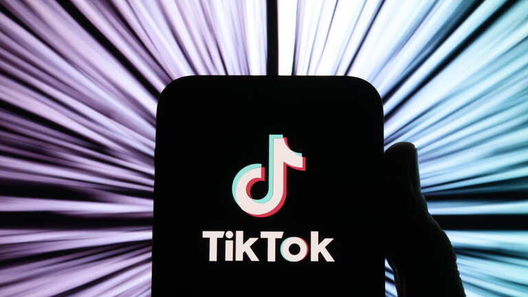 Illustration: TikTok-Logo auf einem schwarz gemalten Smartphone vor buntem Hintergrund