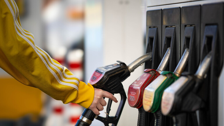 Eine Frau greift zu einer Zapfsäule