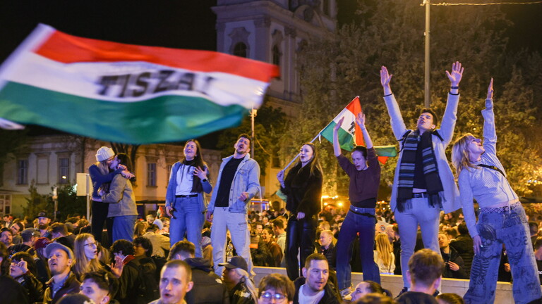 Junge Leute stehen auf einer Mauer und schwenken Ungarn-Flaggen nach dem Wahlsieg von  Péter Magyar (Budapest 13.04.2026)