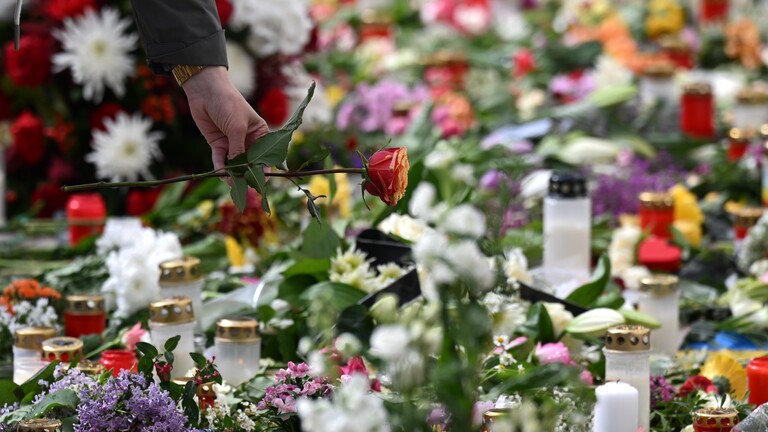 Nach der mutmaßlichen Amokfahrt in der Leipziger Innenstadt haben Menschen Blumen und Kerzen abgelegt. Eine Hand ist zu sehen, die eine Rose dazulegt.