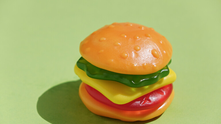 Ein etwa 5x5 cm Schaumzuckerbonbon in Form eines Burgers, bestehend aus Glukosesirup, Zucker und Gelatine.