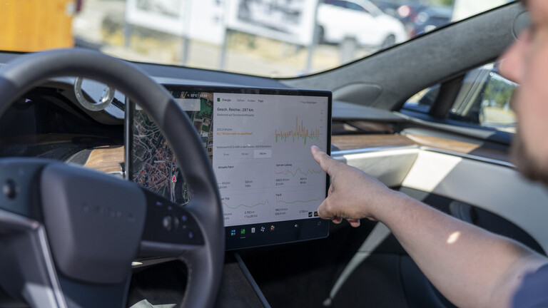 Ein Mann bedient während er Auto fährt einen Touchscreen.