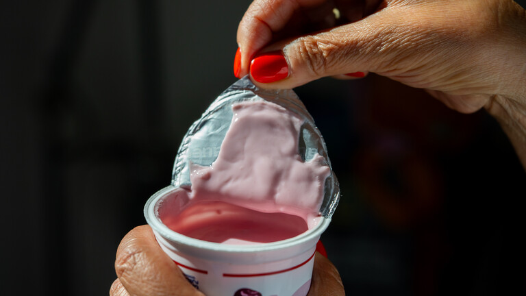 Eine Frau oeffnet am 28.07.2026 in Berlin einen Becher Kirschjoghurt.