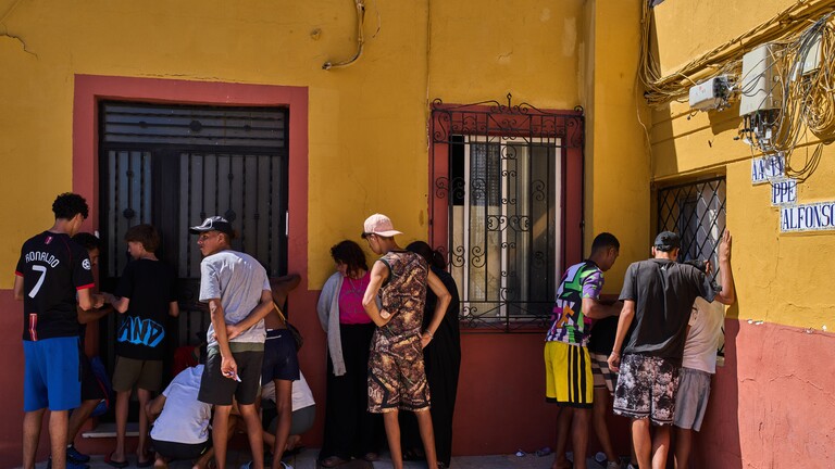 Migranten, darunter auch unbegleitete Minderjährige, die von Marokko nach Spanien eingereist sind, notieren am Dienstag, dem 4. August 2026, ihre Kontaktdaten, um sie einem Nachbarschaftsverein in der spanischen Enklave Ceuta zu übergeben.