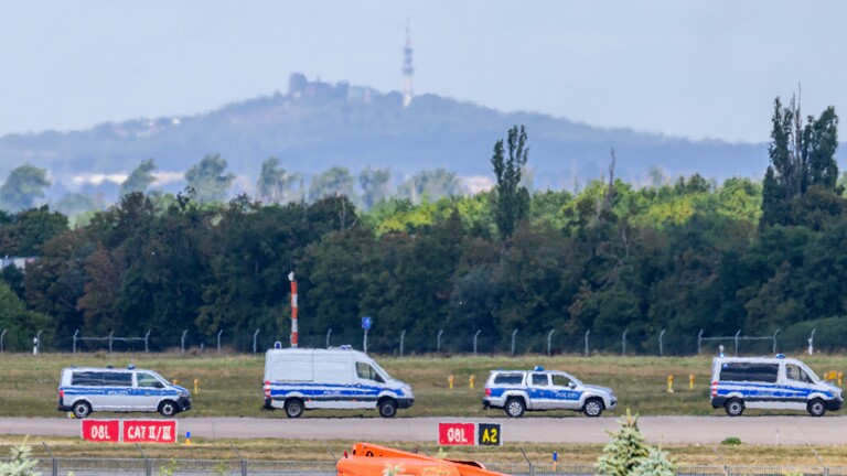 Vor der Silhouette des Petersberges fahren Einsatzkräfte der Polizei entlang der Start-und-Lande-Bahn Nord des Flughafens Leipzig/Halle.