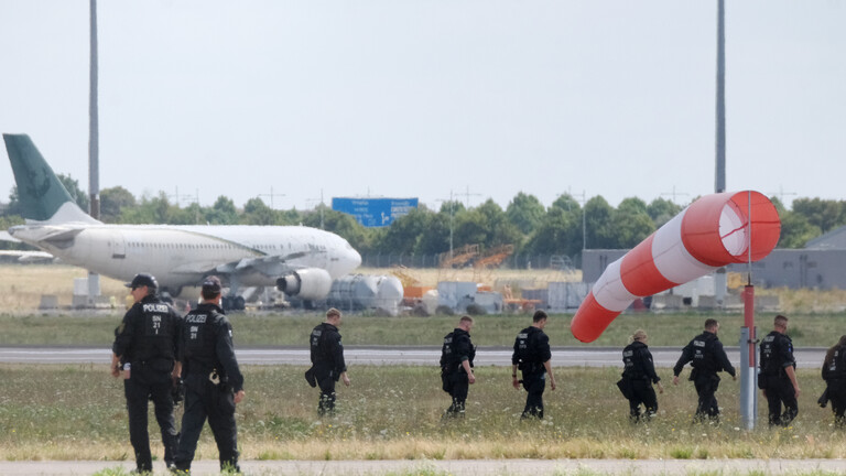Polizisten gehen über eine Wiese auf dem Gelände des Flughafen Leipzig/Halle (7.08.2026)