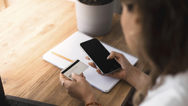Eine Frau hält Smartphone und Kreditkarte in den Hand.
