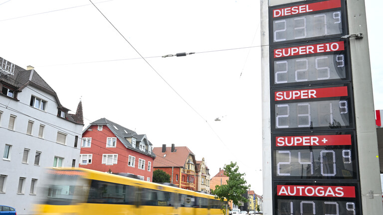 Preistafel einer Tankstelle. Links fährt eine Straßenbahn vorbei.