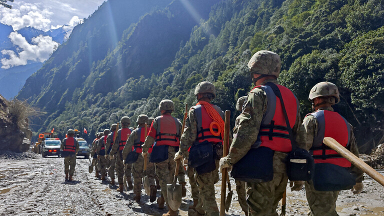 Soldaten der chinesischen Volksbefreiungsarmee laufen durch ein Tal, der Boden ist mit Schlamm überzogen. Es ist eine Rettungsaktion nach der Sturzflut, die auch Tibet getroffen hat.