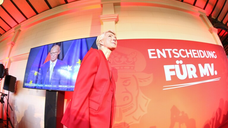 Landtagswahl in Mecklenburg-Vorpommern 2026: Manuela Schwesig läuft auf der SPD-Wahlparty an einem Monitor vorbei, auf dem Bundeskanzler Merz zu sehen ist.